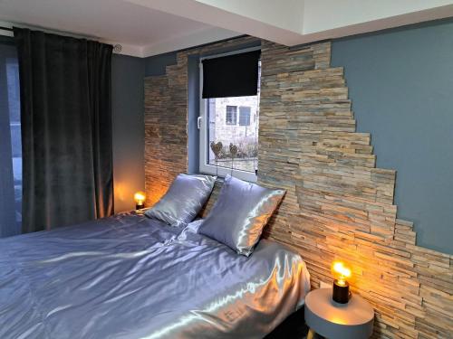 1 dormitorio con 1 cama grande y pared de piedra en Gîte 'Toi et moi ' en Graux