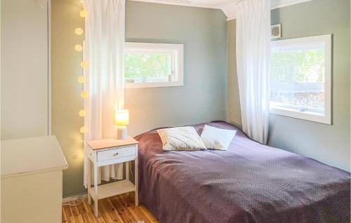 a bedroom with a purple bed with a nightstand and two windows at Cozy Home In rebro With Wifi in Örebro