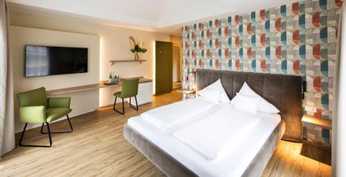 a hotel room with a bed and chairs and a tv at Hotel Himmelreich in Wals