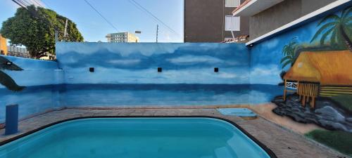 a swimming pool with a mural on the side of a building at Pousada Primeiro Sol in João Pessoa