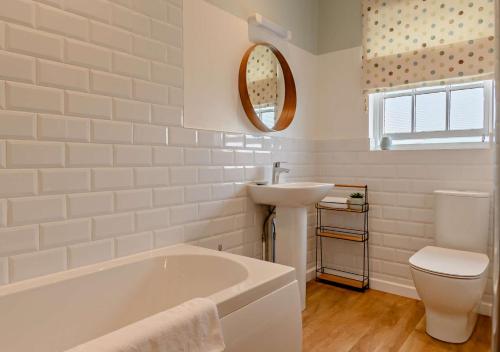 a white bathroom with a tub and a sink at Skyes House in Southwold