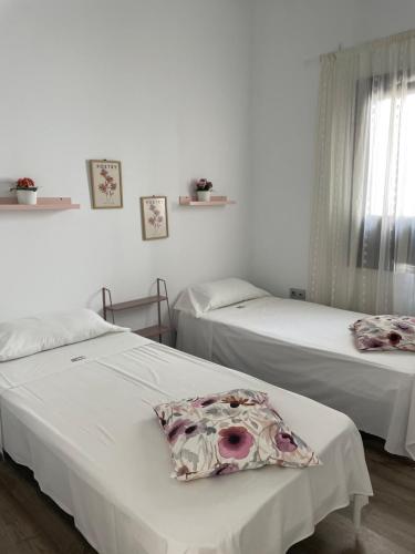 2 camas en una habitación con paredes blancas en The Cathedral Hostel, en Murcia