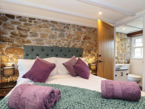 a bedroom with a large bed with purple pillows at The Hayloft in Helston