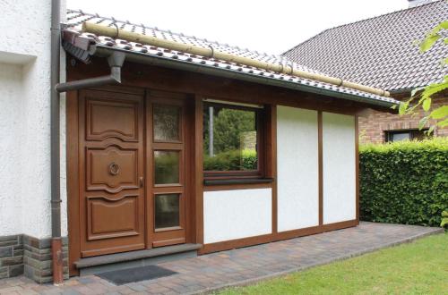 a house with a wooden door and two windows at Ferienwohnung Reifferscheid in Hellenthal