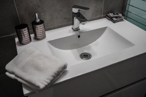 a white bathroom sink with a towel on it at Silver Central Apartment in Volos