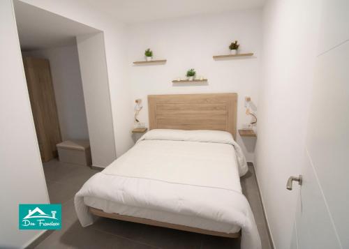 a small bedroom with a bed and two plants on shelves at Don Francisco in Córdoba