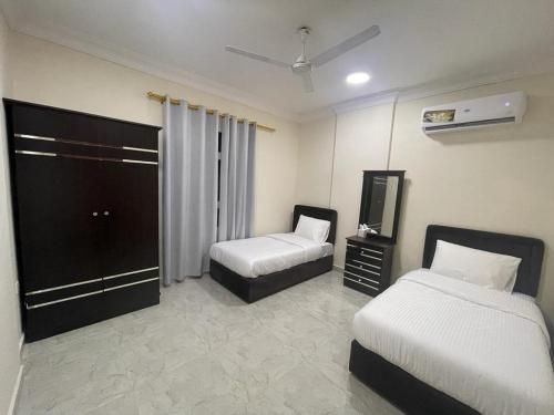 a hotel room with two beds and a television at Red-15 - Bn Saif in Salalah