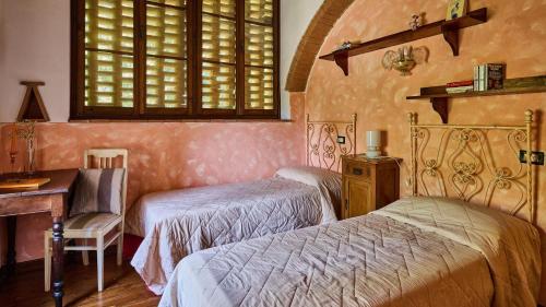 a bedroom with two beds and a desk and a window at San Martino in Certaldo