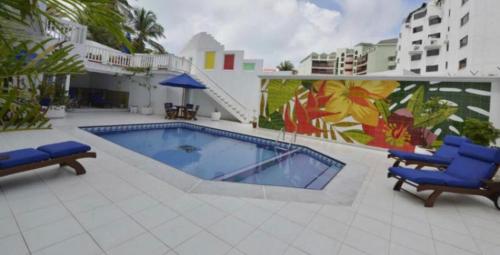 a swimming pool with two blue chairs next to a building at Lovely Penthouse with incredible view in San Andrés