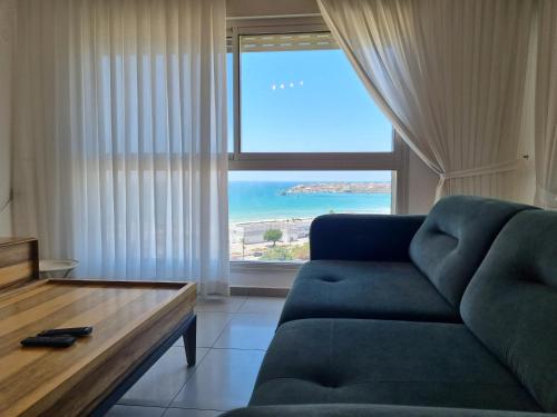 a living room with a couch and a large window at Ducks on the beach in ‘Akko