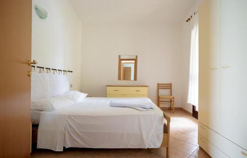 1 dormitorio con cama blanca y espejo en Residence Agrifoglio, en Monte Petrosu