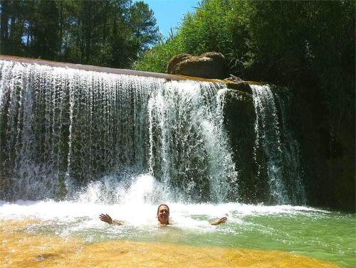 two people in the water in front of a waterfall at Forest Days in Navés
