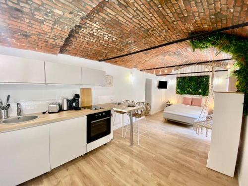 une cuisine avec des armoires blanches et un salon dans l'établissement Les Amourettes, à Rouen