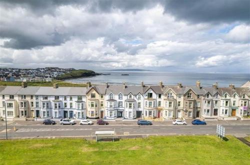 a row of houses in a parking lot next to the water at Portrush by the Sea - 3 West Beach in Portrush