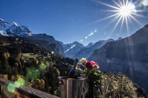 a vase with flowers on a balcony with a view of mountains at Chalet Aargovia South in Wengen