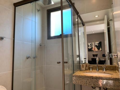 a bathroom with a shower and a sink and a mirror at Rio Marina Resort in Itacuruçá
