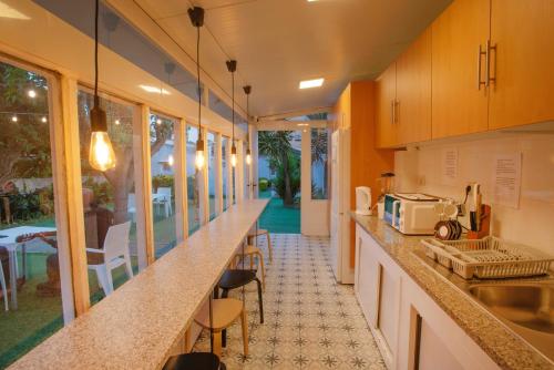 a kitchen with a counter with a sink and some chairs at Hostel das Flores in Senhora da Hora