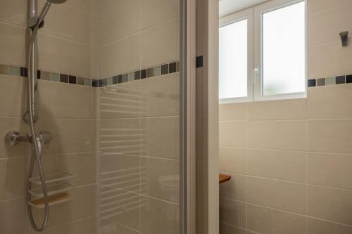 uma casa de banho com um chuveiro e uma porta de vidro em Le Dionysien *** (petite maison avec terrasse) em Saint-Denis-de lʼHôtel