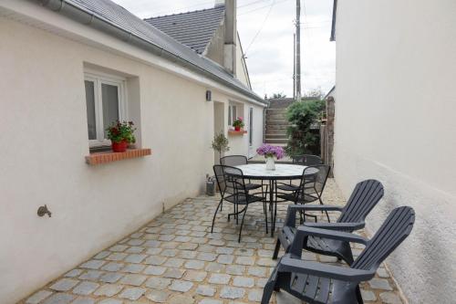 un patio avec une table et des chaises sur un patio dans l'établissement Le Dionysien *** (petite maison avec terrasse), à Saint-Denis-de-l'Hôtel