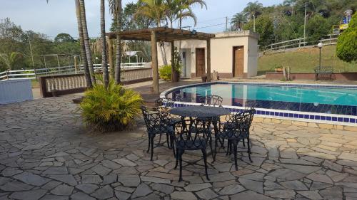 a patio with a table and chairs next to a pool at Pousada Kart Clube in São João del Rei