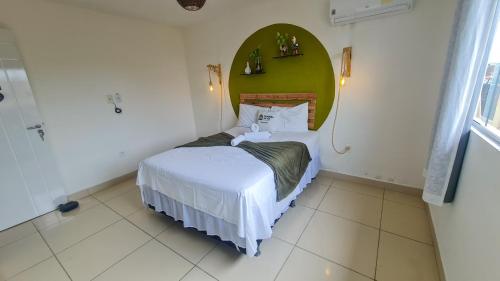 a small bedroom with a bed with a green headboard at Cantinho da Gê Suítes in Porto De Galinhas