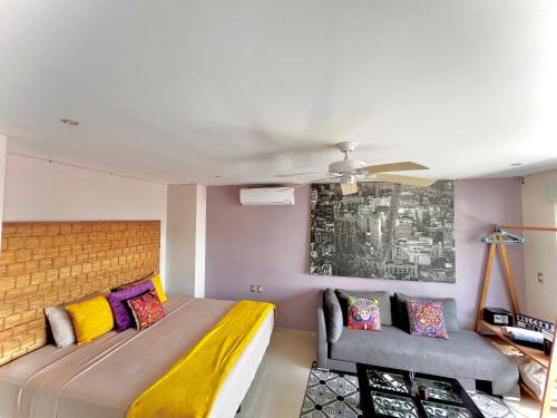 a bedroom with a bed and a couch and a ceiling fan at Playa Centro Rooftop Apartments & Studios in Playa del Carmen