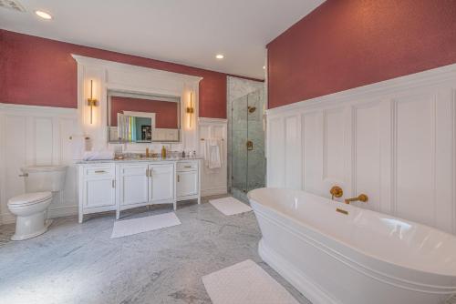 a bathroom with a tub and a toilet and a sink at Orman Mansion - Pueblo's Most Luxurious Stay! in Pueblo