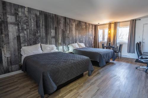a bedroom with two beds and a wooden wall at Le 2020 Charlevoix in La Malbaie