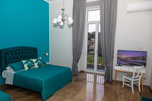 um quarto azul com uma cama e uma secretária com uma televisão em Villa Giuseppina em Nápoles
