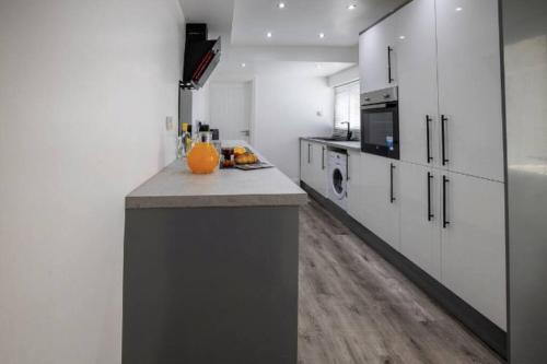a kitchen with white cabinets and an orange pumpkin on a counter at Abingdon House Workstays UK in Middlesbrough
