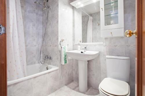a bathroom with a toilet and a sink and a tub at Fantástico apartamento en la playa. A/A y vistas in Pineda de Mar