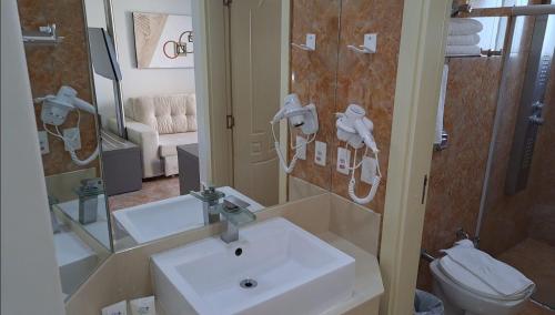 a bathroom with a sink and a toilet and a mirror at Thermas diRoma c entrada Acqua Park in Caldas Novas