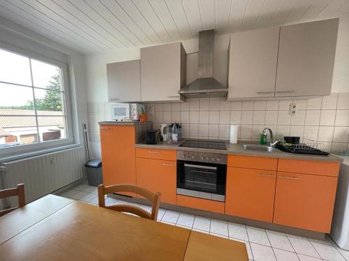 a kitchen with orange cabinets and a sink and a table at Ferienwohnung Unter den Linden in Halbe