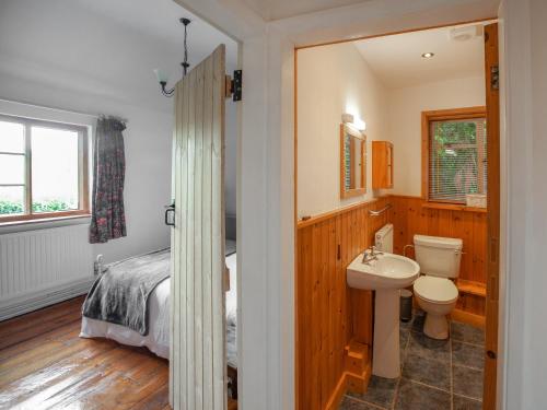 a bedroom with a bed and a sink and a toilet at The Cottage in Stockton on Teme