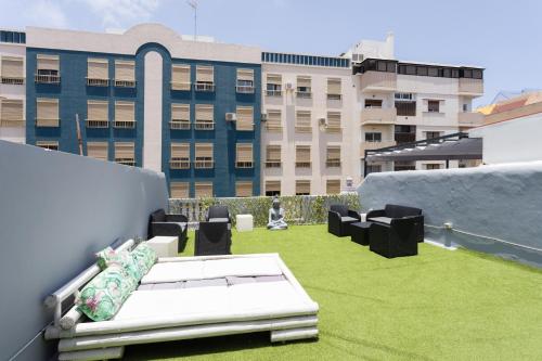 a rooftop patio with a couch and chairs on the grass at Wanderlust Hostel in Santa Cruz de Tenerife