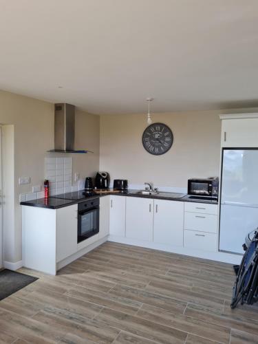 a kitchen with white cabinets and a clock on the wall at sea view apartment in Letterkenny