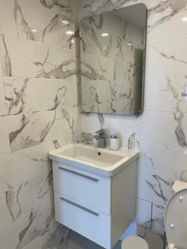W białej łazience znajduje się umywalka i lustro. w obiekcie Apartments City View w mieście Igalo