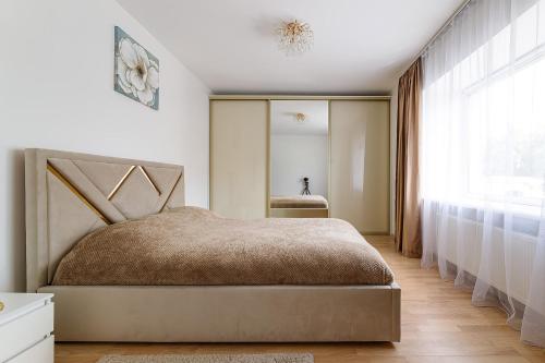 a bedroom with a bed and a large window at Naukova Street Appartamento in Lviv