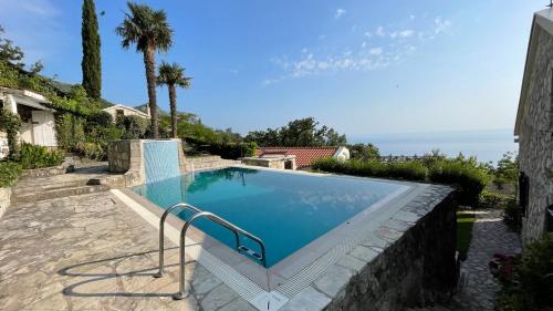 a swimming pool in a yard with a stone wall at House in the Mountains near Budva in Budva