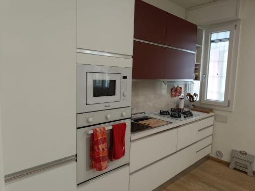 a white kitchen with a stove and a microwave at La CASA di LUCA-Fiera e Stazione-Private Parking in Bologna