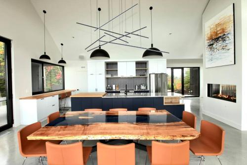 a kitchen with a large dining table and orange chairs at L'Auguste - Luxe et confort in Petite-Rivière-Saint-François