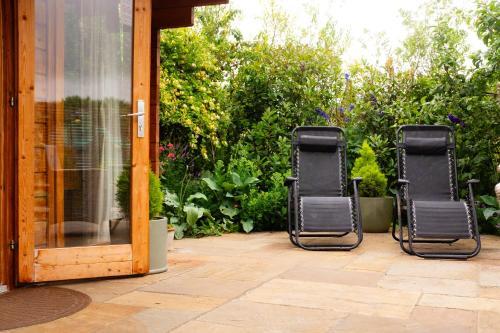 two black chairs sitting on a patio at Moors Wood Relaxing ,Tranquil retreat with Hot Tub in Chippenham