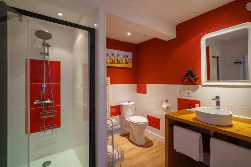 a bathroom with red walls and a toilet and a sink at Abri du Pêcheur in La Forêt-Fouesnant