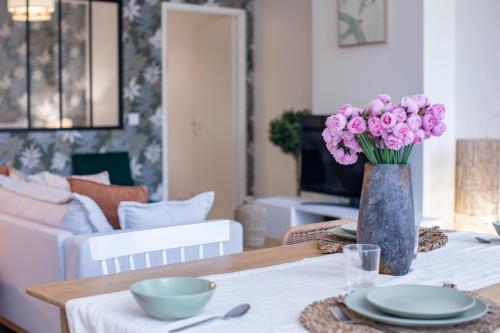 a dining room table with a vase of pink flowers at La Bouverie in Romans-sur-Isère