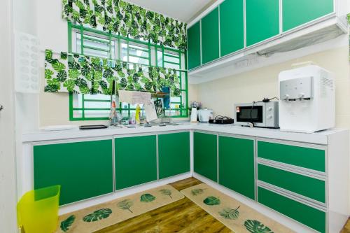 a green and white kitchen with green cabinets at Desaru 16Pax Family with Private Mini Pool & Jacuzzi in Kota Tinggi