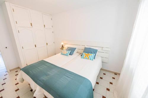 ein Schlafzimmer mit einem weißen Bett mit blauen Kissen in der Unterkunft Nublo in Las Playitas