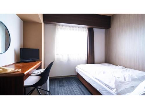 a bedroom with a bed and a desk and a computer at Hotel AreaOne Minamisoma - Vacation STAY 56244v in Minamisouma