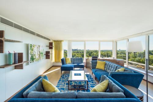 a living room with blue furniture and large windows at COMO Metropolitan London in London