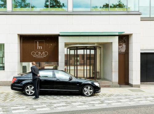 倫敦的住宿－倫敦大都會COMO酒店，站在一座大楼前的一辆黑色汽车旁的人