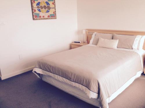 a bedroom with a white bed with a picture on the wall at Wytonia Beachfront Accommodation in Port Fairy